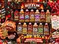 Ultimate Meltdown holiday pre-sale: 13 unique 500 mL sauces with original label artwork, plus the owner holding a Waaburger & Cries display bottle with a white cap.